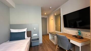 Une chambre d’hôtel moderne équipée d’un lit, d’un bureau, d’une chaise et d’un téléviseur.