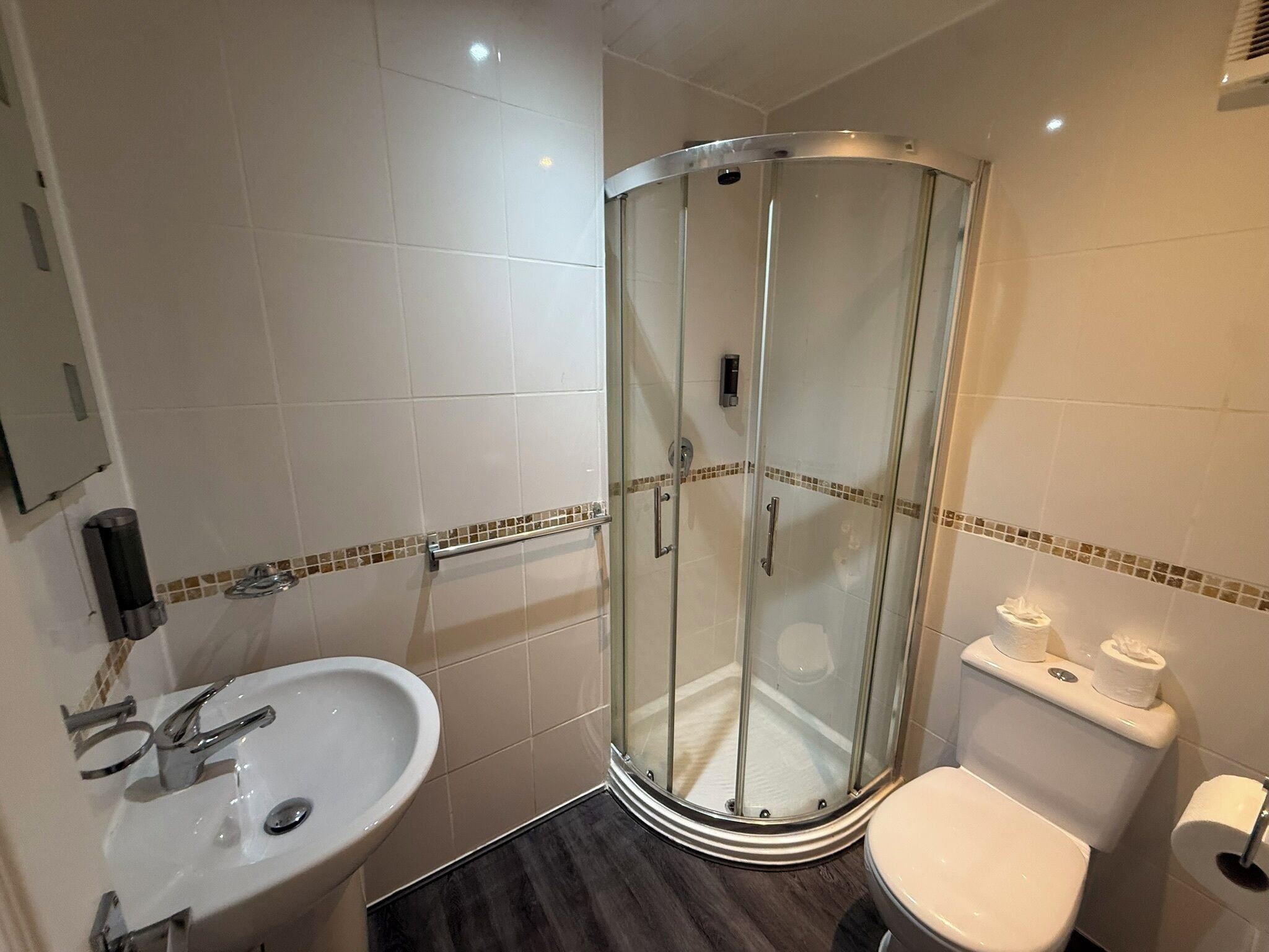 Un baño con ducha de vidrio, lavamanos e inodoro.