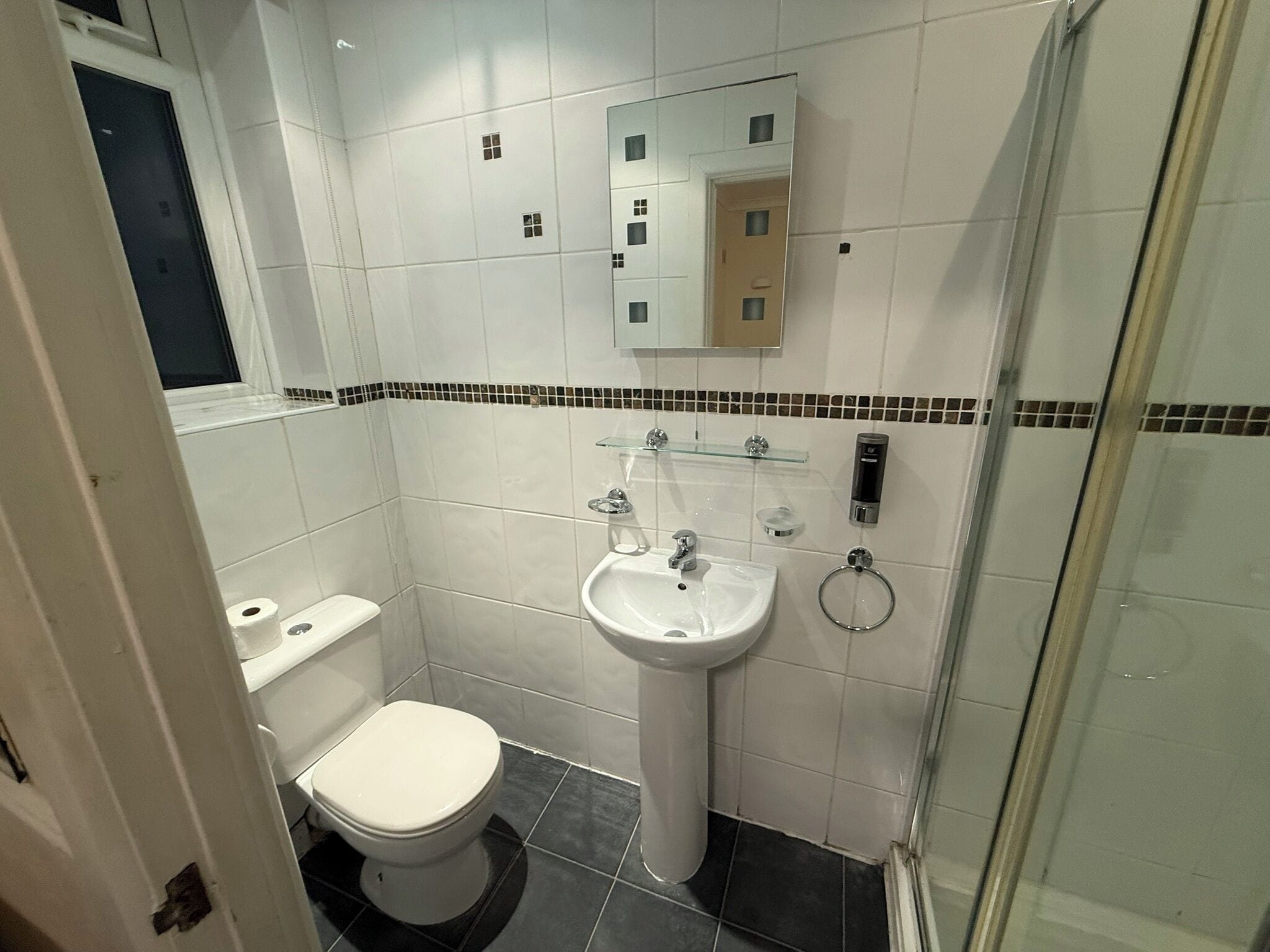 A bathroom with a toilet, sink, and shower.