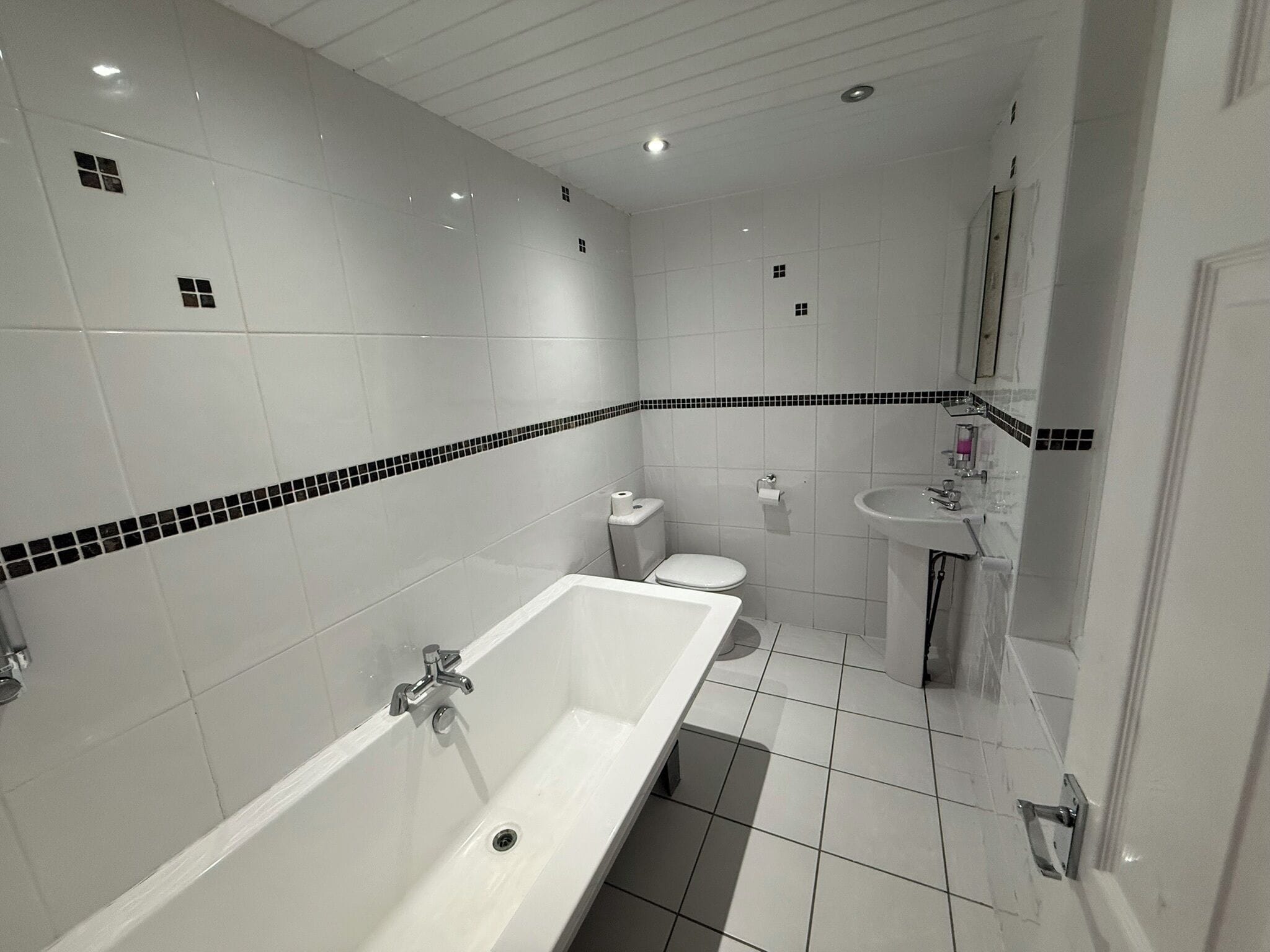 A bathroom with a bathtub, toilet, sink, and tiled walls.