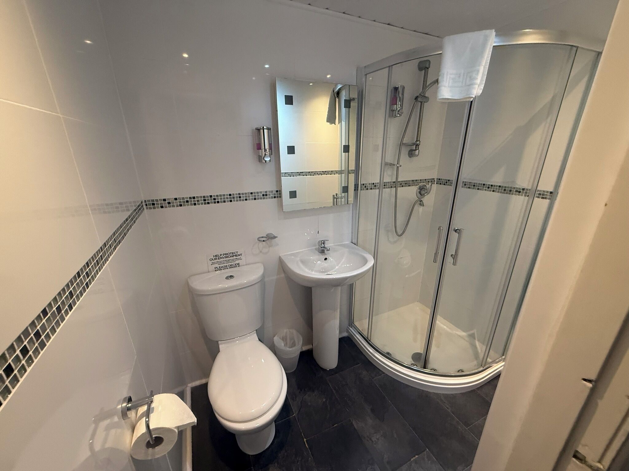 A bathroom with a toilet, sink, and glass-enclosed shower.