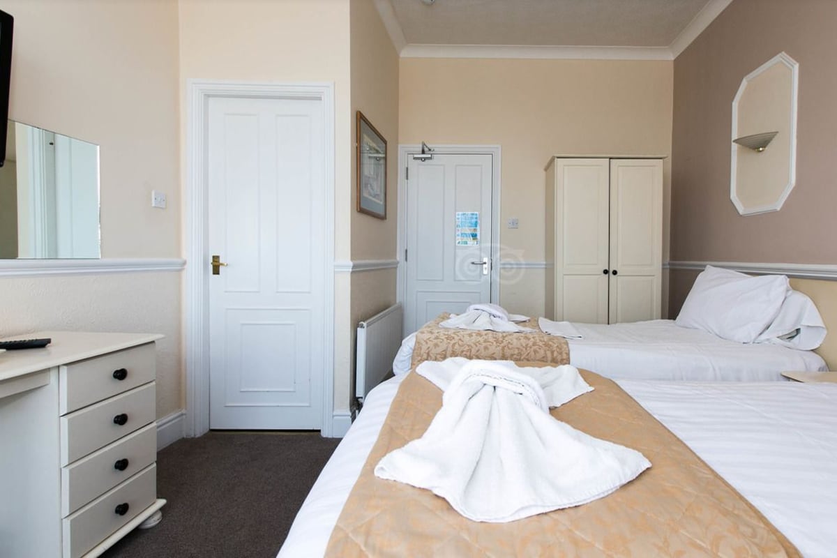 A hotel room with a bed, a bedside table, a dresser, and a wardrobe.