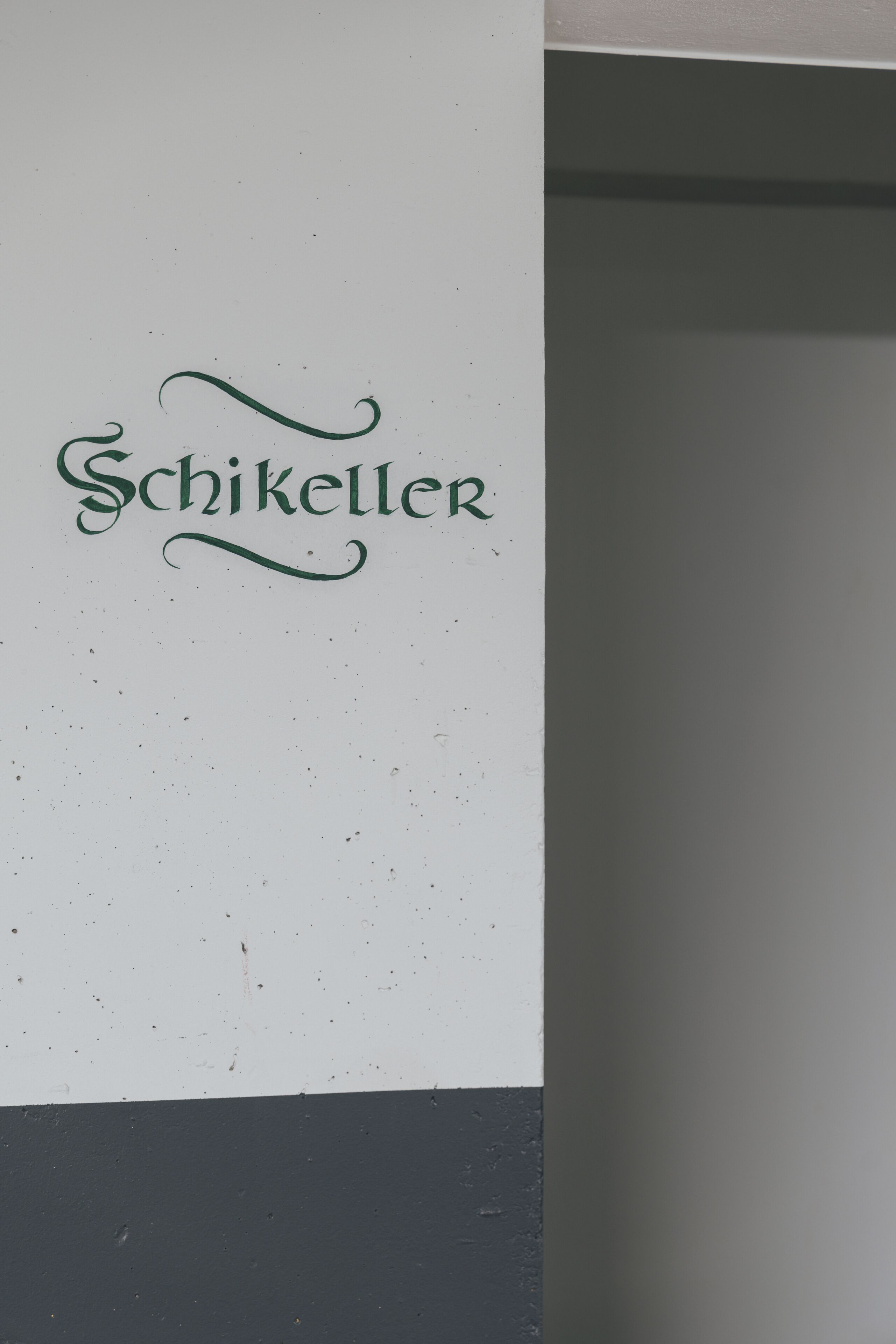 A wall with the name 'Schikeller' in stylized lettering.