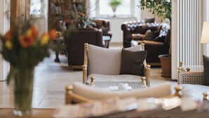 A cozy living room with a plush armchair, a coffee table, and a bookshelf filled with books. - Hotel Garni Bären (Feldkirch)