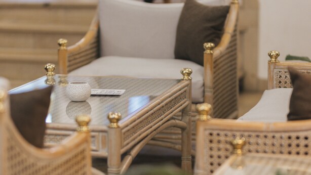 A room with wicker furniture, a small table, and a decorative figure in the background. - Hotel Garni Bären (Feldkirch)
