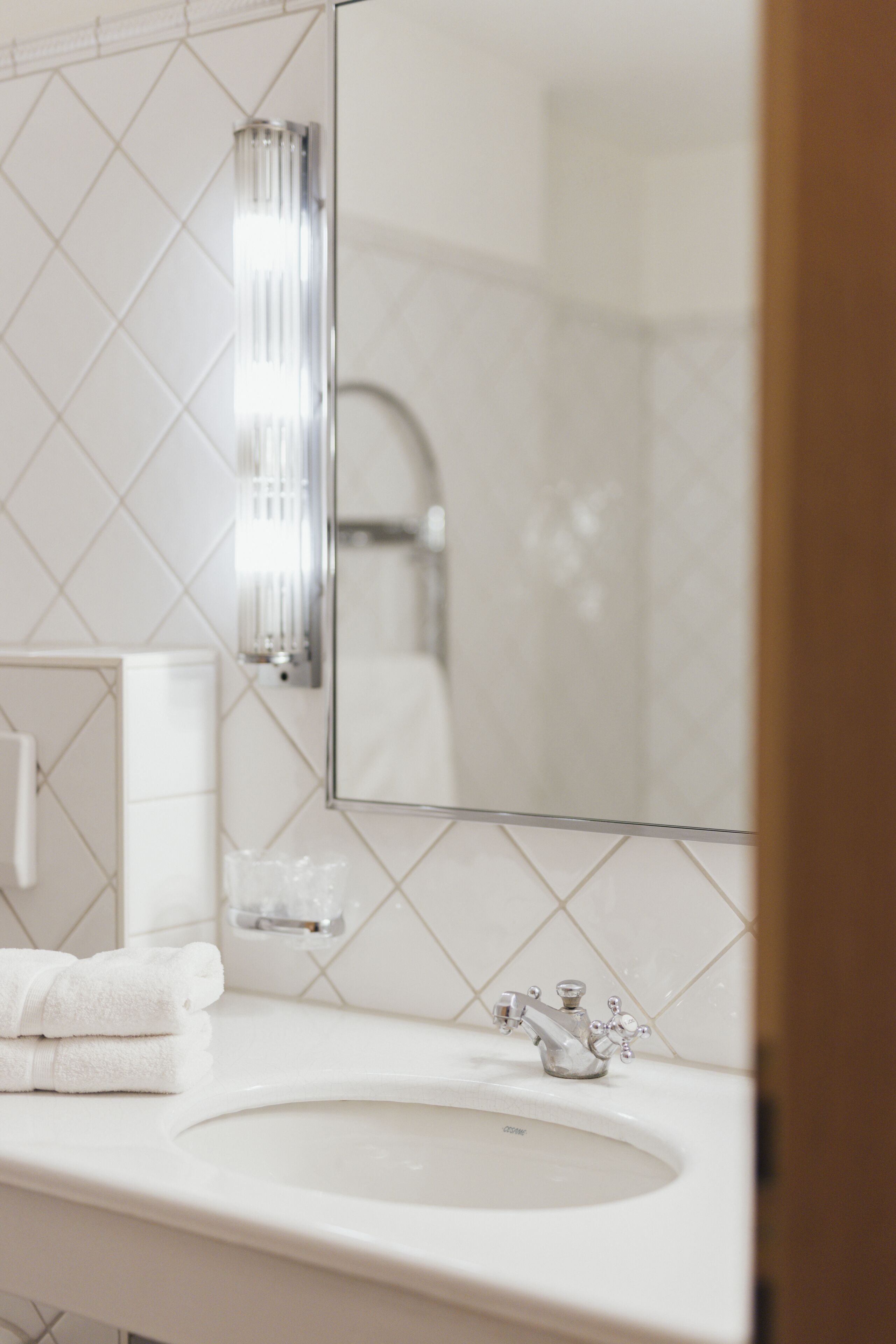 Une salle de bain avec un lavabo blanc, un miroir et un porte-serviettes.