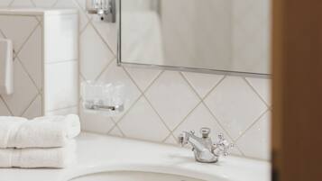 Une salle de bain avec un lavabo blanc, un miroir et un porte-serviettes.