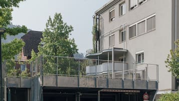 Ein Gebäude mit überdachtem Parkbereich, einem umzäunten Balkon und einem Schild, das eine Parkzeitbegrenzung von 10 Minuten anzeigt.
