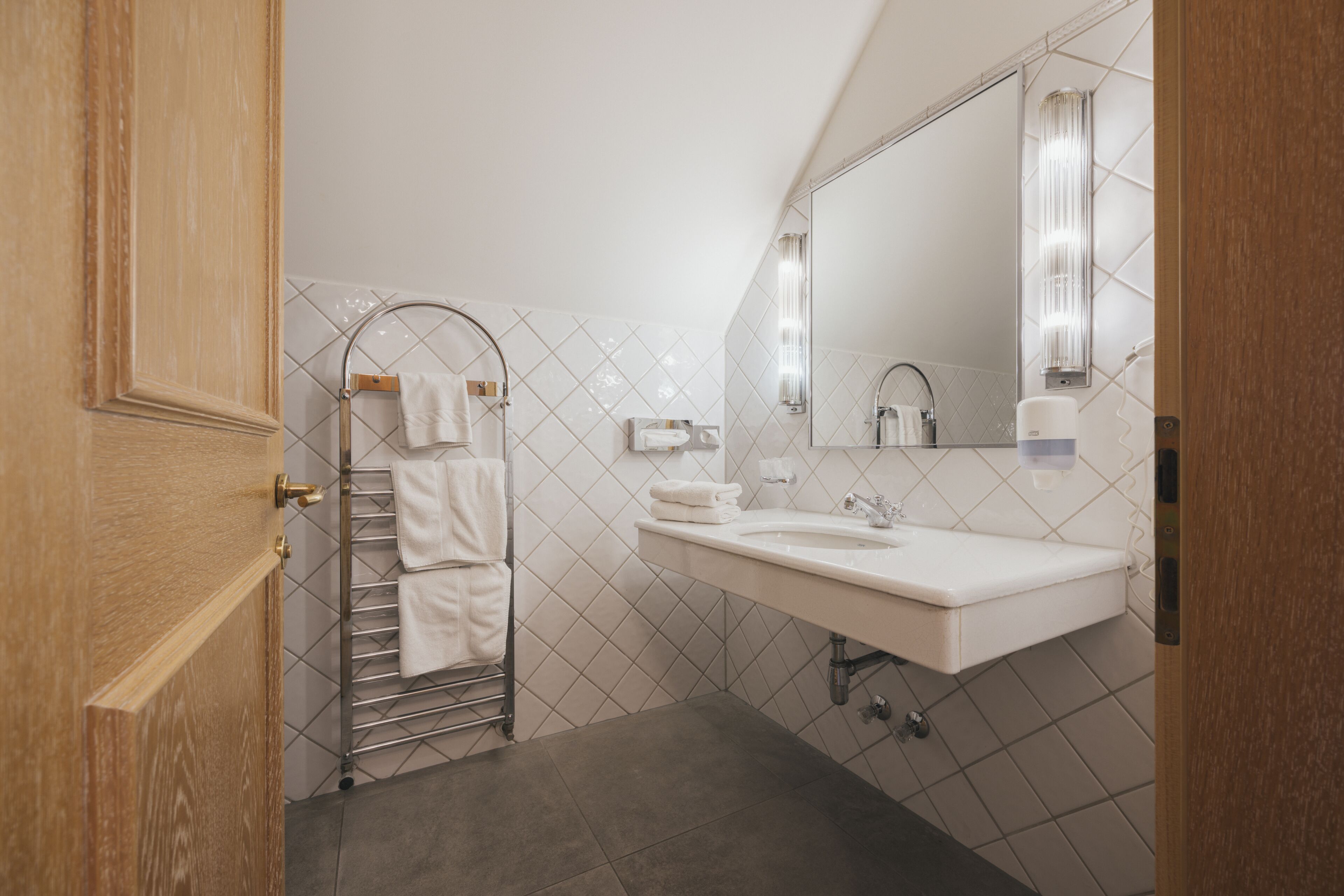 A modern bathroom with a white sink, a mirror, and a towel rack.