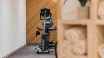 A modern spa room with a stationary bike, wooden panel walls, and neatly arranged towels.