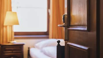 A hotel room with a bed, a nightstand with a lamp, and a window with curtains.