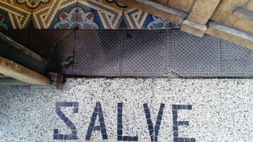 Un sol en mosaïque orné du mot « SALVE » et un plafond à motifs au-dessus.