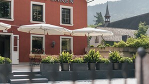 A red building with the sign "HOTEL BÄREN" and outdoor seating with umbrellas. - Hotel Garni Bären (Feldkirch)