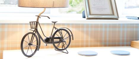 Una bicicleta con una cesta, una lámpara y un documento en un marco sobre un alféizar.