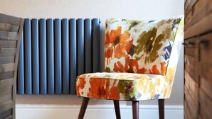 Kukkakuviollinen tuoli huoneessa, jossa on patteri ja puupaneloidut seinät.