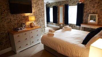 Enjoy a comfortable stay in this well-appointed room featuring a large bed, dresser, flat-screen TV, and a table with a lamp.