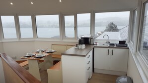 Une cuisine moderne avec un coin repas, de grandes fenêtres et une vue sur un lac.
