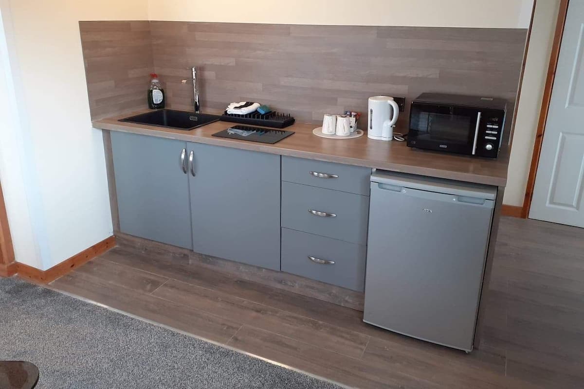 Een kleine keuken met een spoelbak, magnetron en vaatwasser.