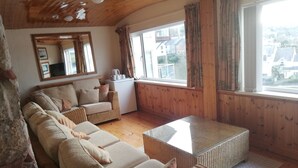 Un salon confortable avec un ensemble de canapés, une table basse et une grande fenêtre agrémentée de rideaux.