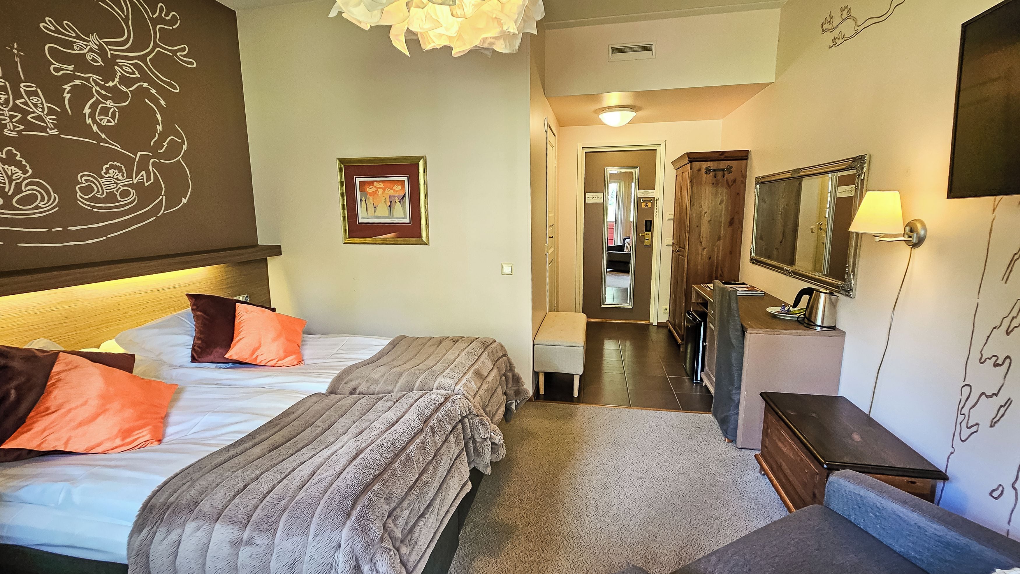 Ein Hotelzimmer mit zwei Betten, einem Schreibtisch, einem Spiegel und einem durchgegangenen Tür sichtbaren Badezimmer.