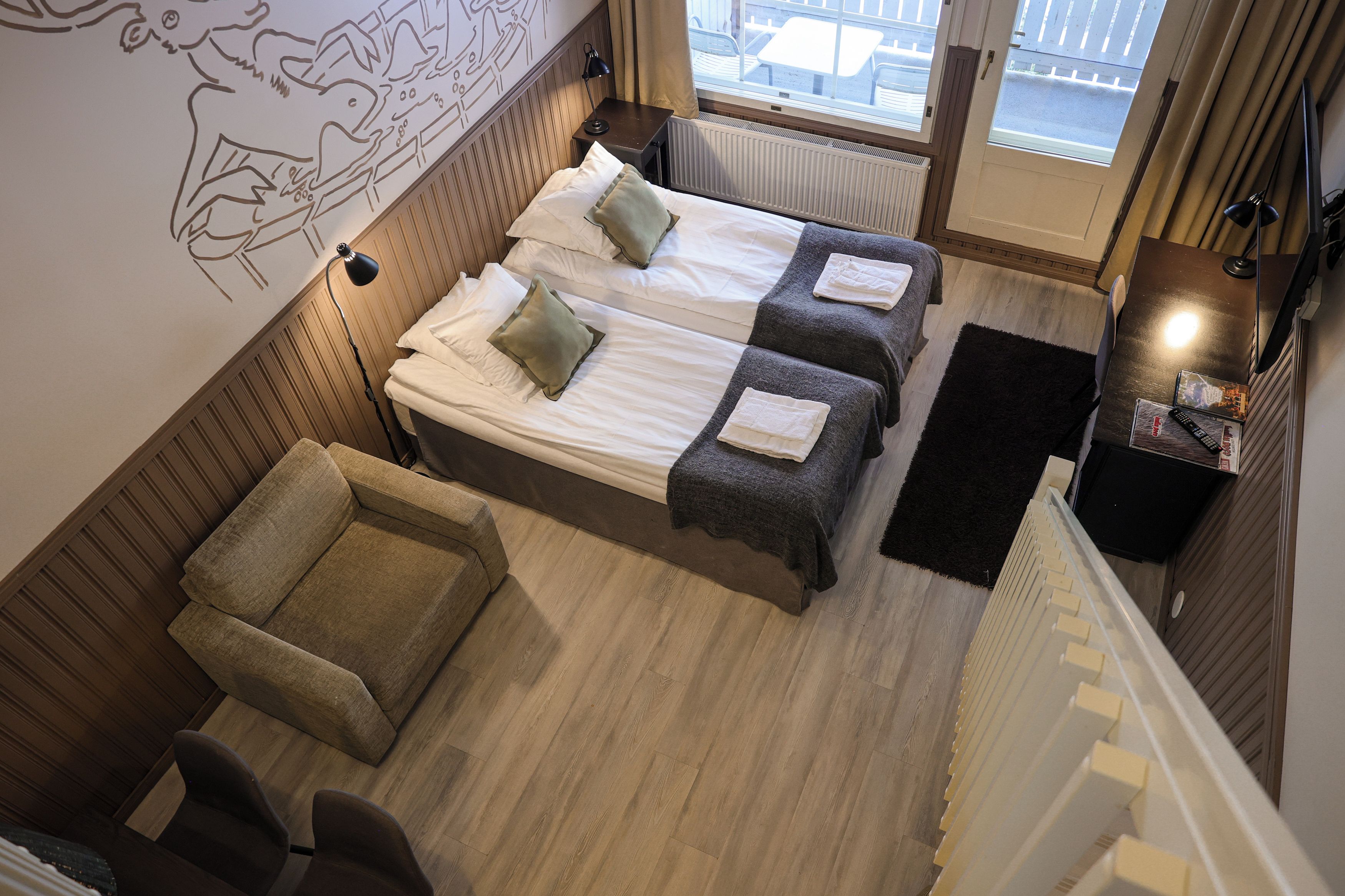 A hotel room with two beds, a sofa, a chair, a black rug, and a wall with a decorative design.