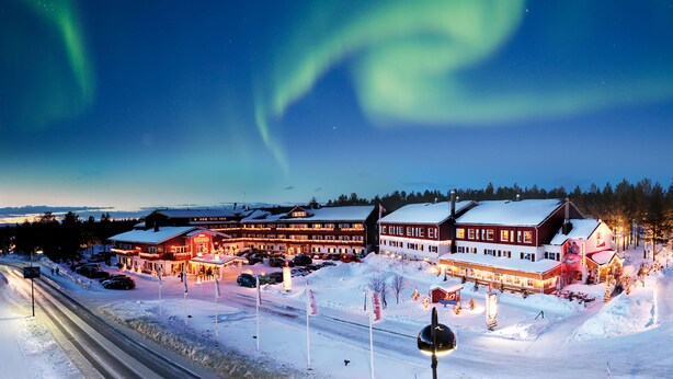 A hotel with multiple buildings, snow-covered surroundings, and a road in the foreground. - Hotel Hullu Poro (Kittila)