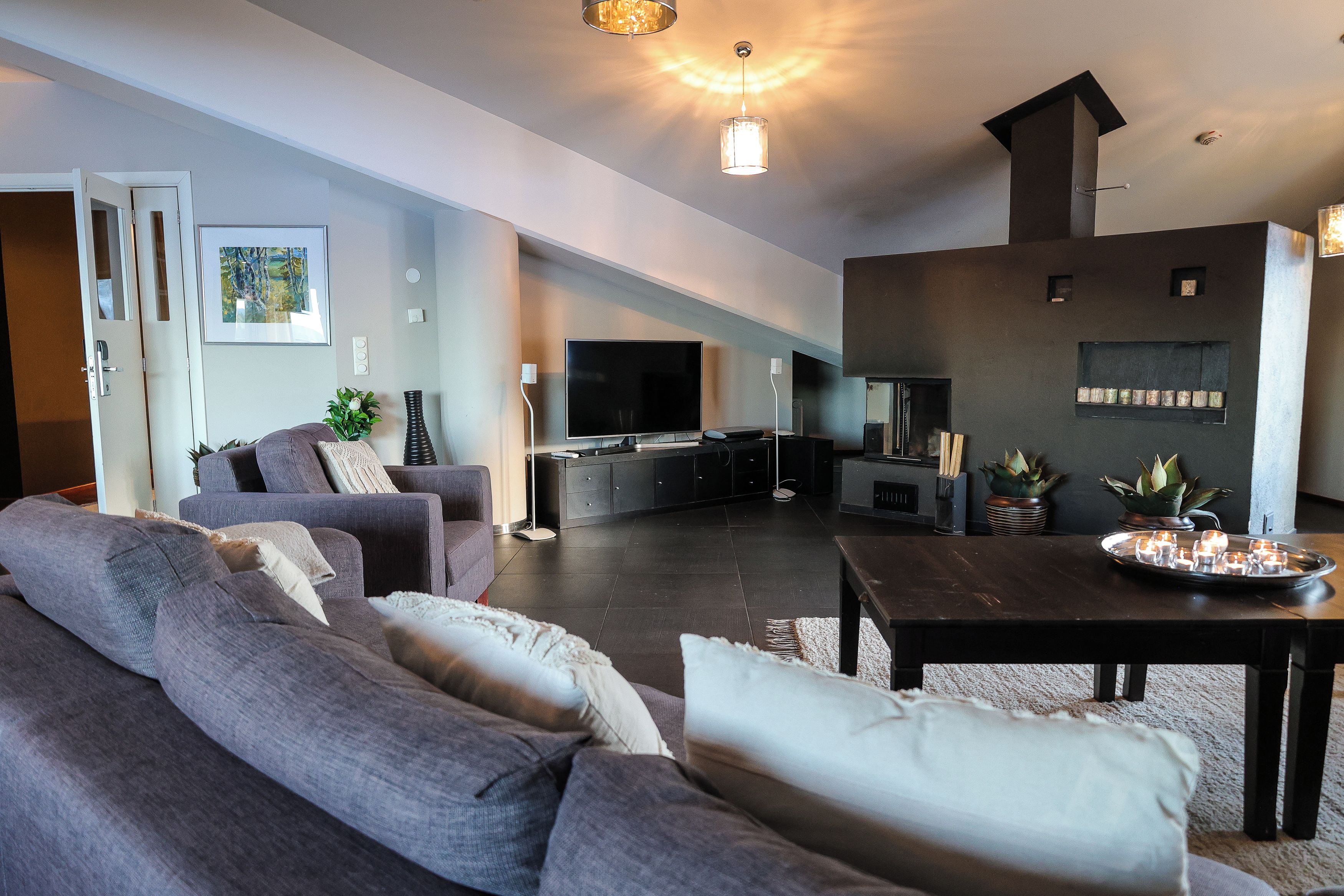A modern living room with a sofa, a coffee table, a flat-screen TV, and a fireplace.