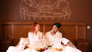 A room with a wooden headboard, a bed with white bedding, and a wall decoration of reindeer. - Hotel Hullu Poro (Kittila)