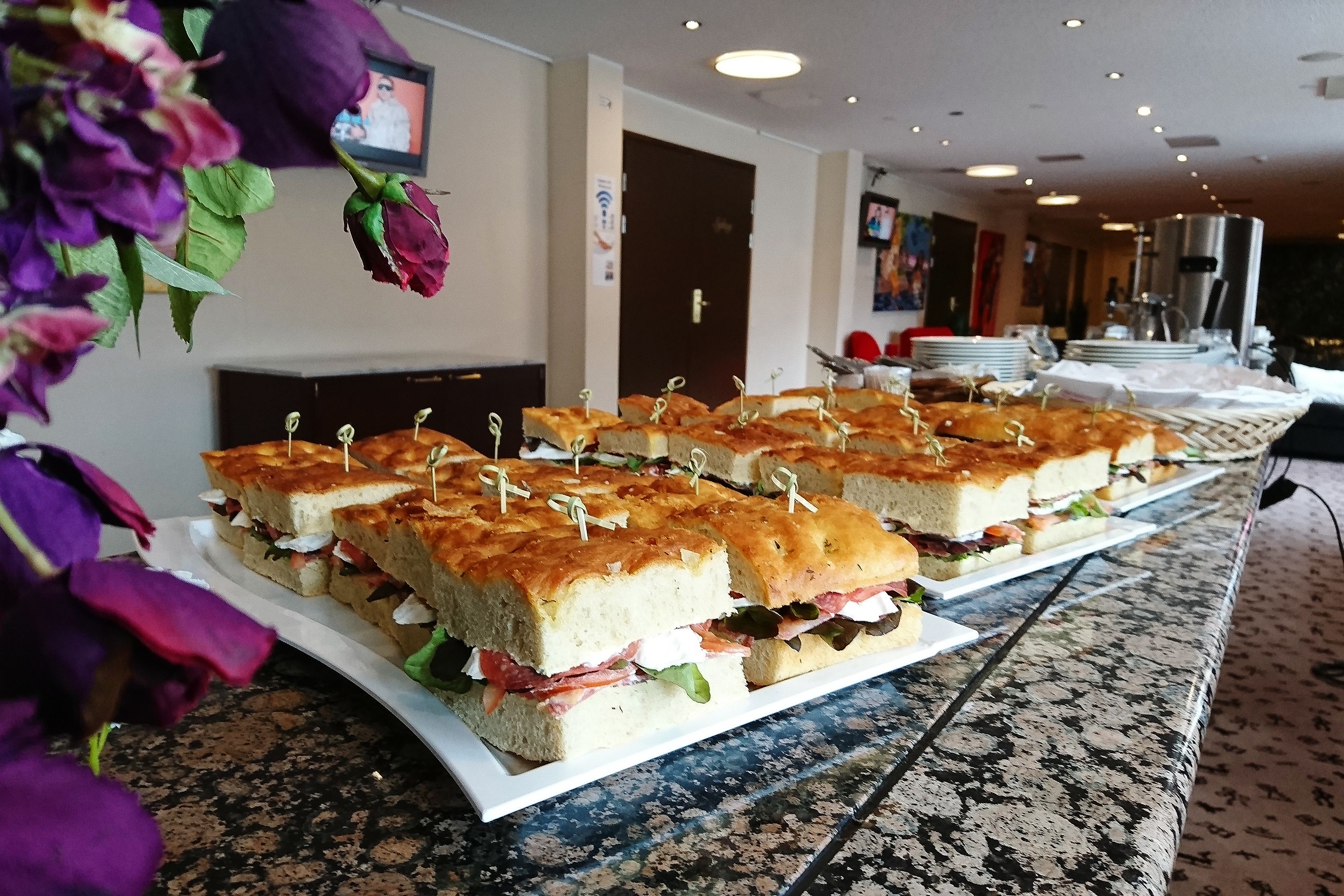 Una mesa de buffet con sándwiches y un arreglo floral.