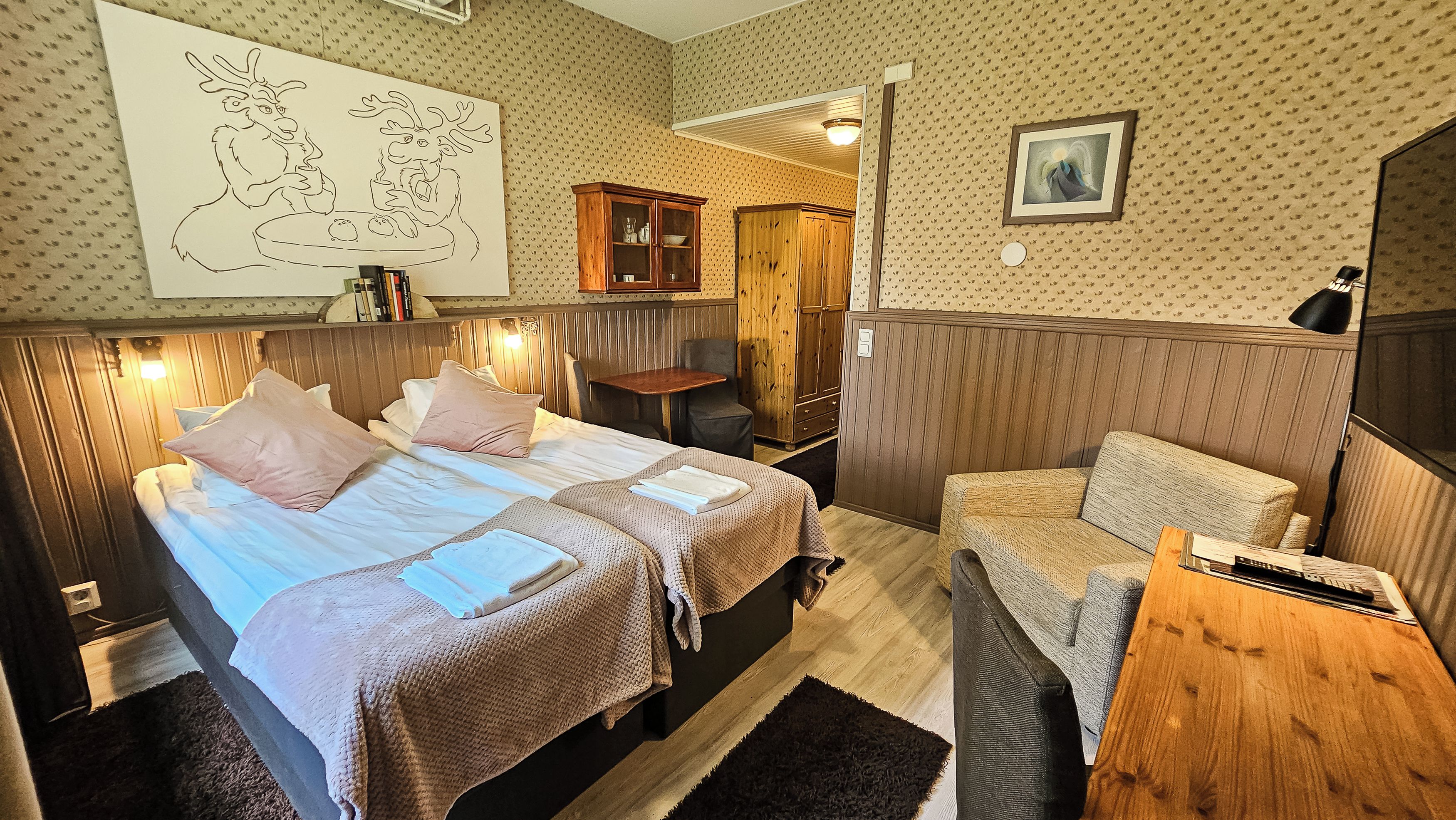 A cozy room with two beds, a wooden cabinet, a small table, and a framed picture on the wall.