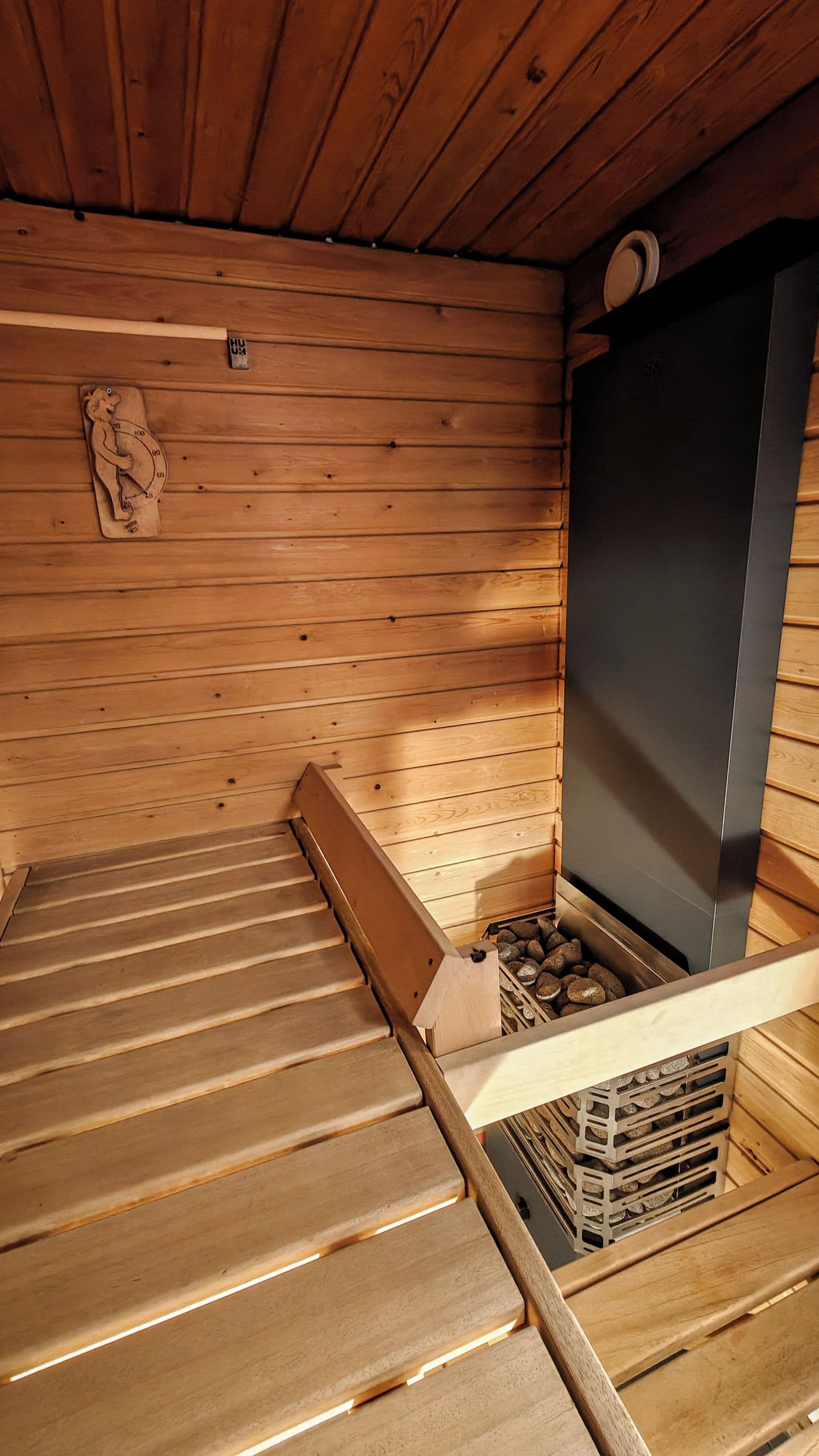 Un interior de madera con sauna, un banco de madera y un calentador de pared.