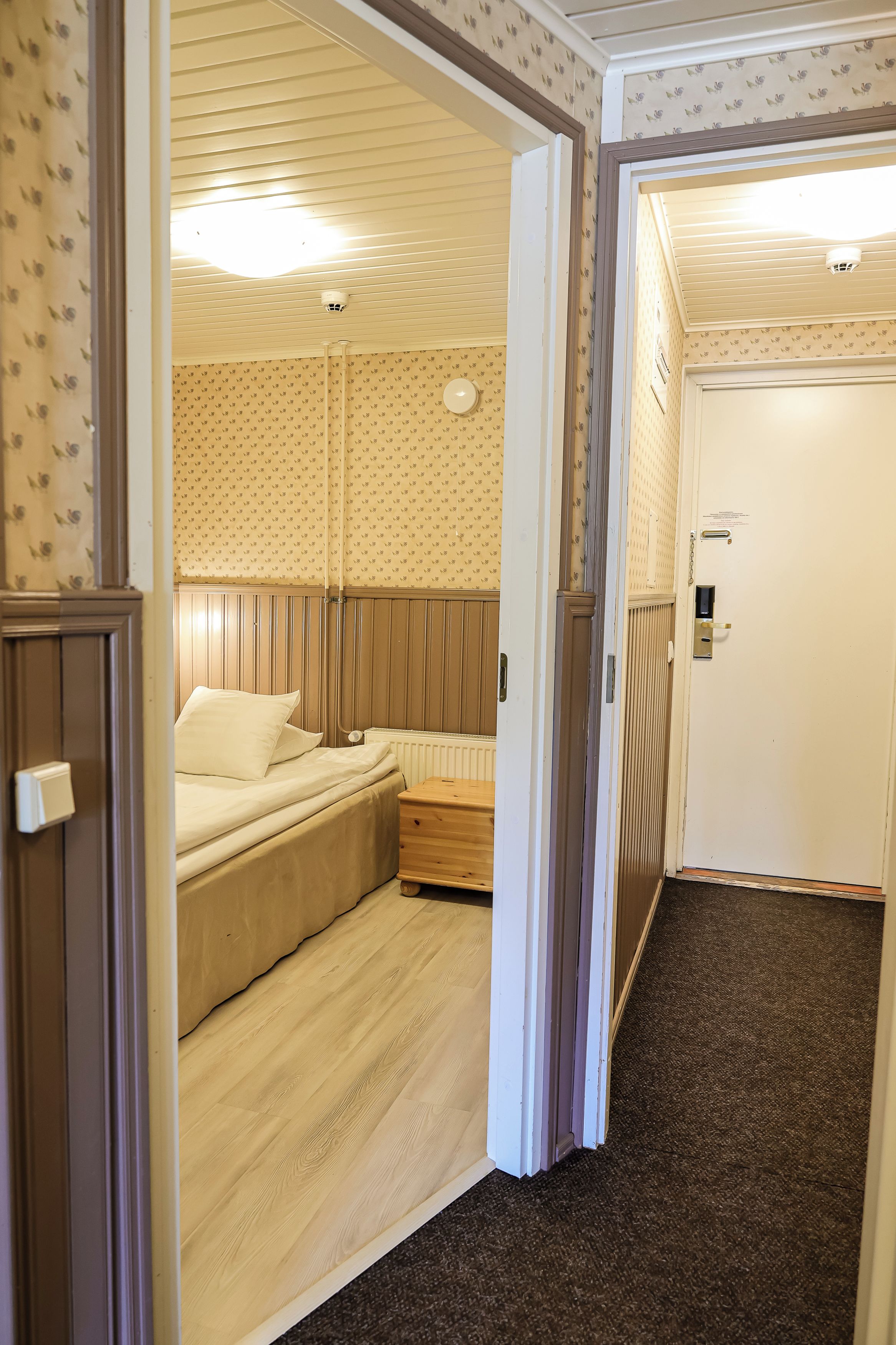 A room with a bed, a bedside table, and a door.
