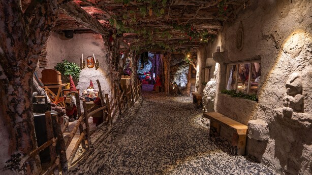 A narrow, rustic interior with stone walls, wooden benches, and a cobblestone floor. - Hotel Hullu Poro (Kittila)