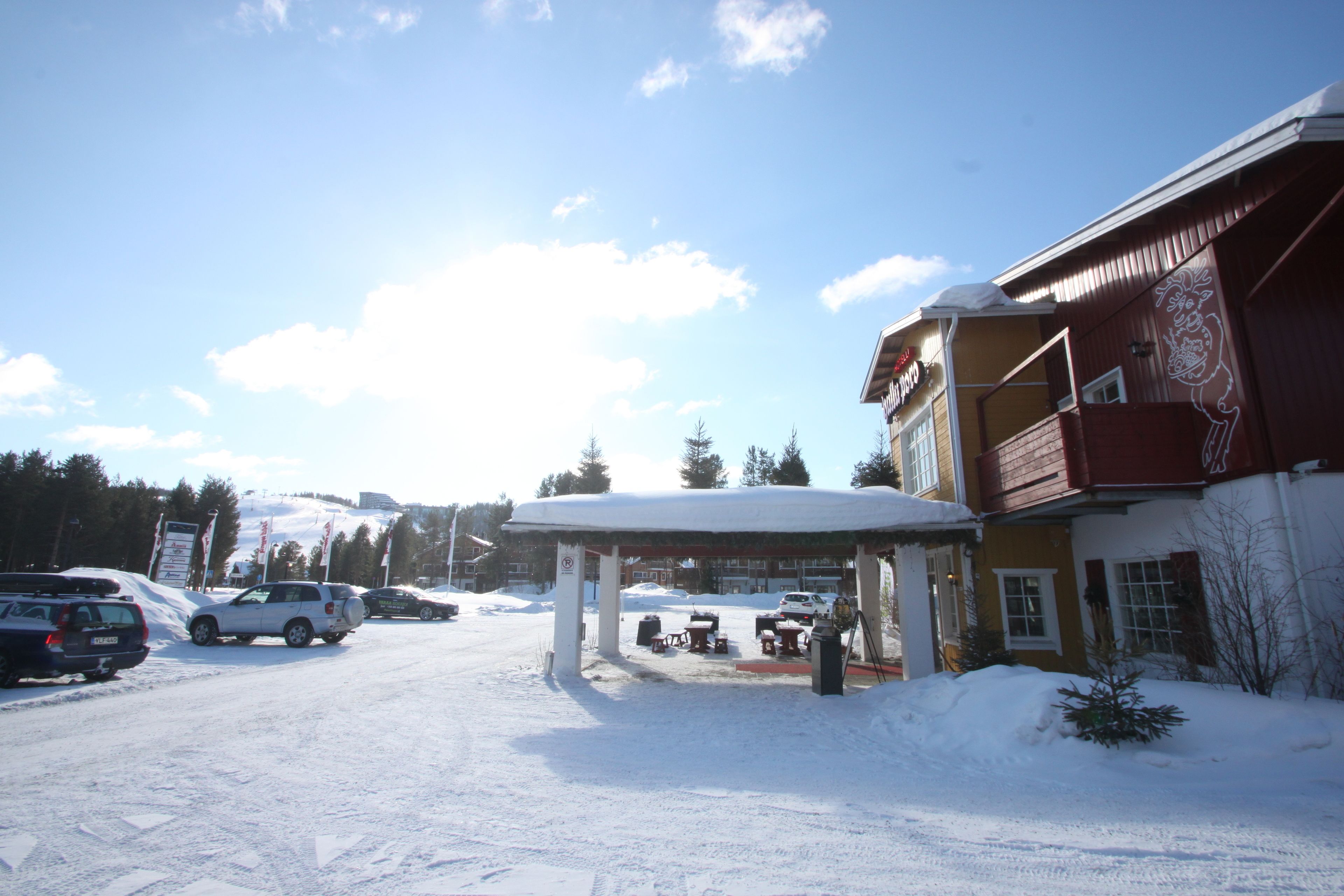 A building with a covered outdoor area, a snow-covered entrance, and parked cars.
