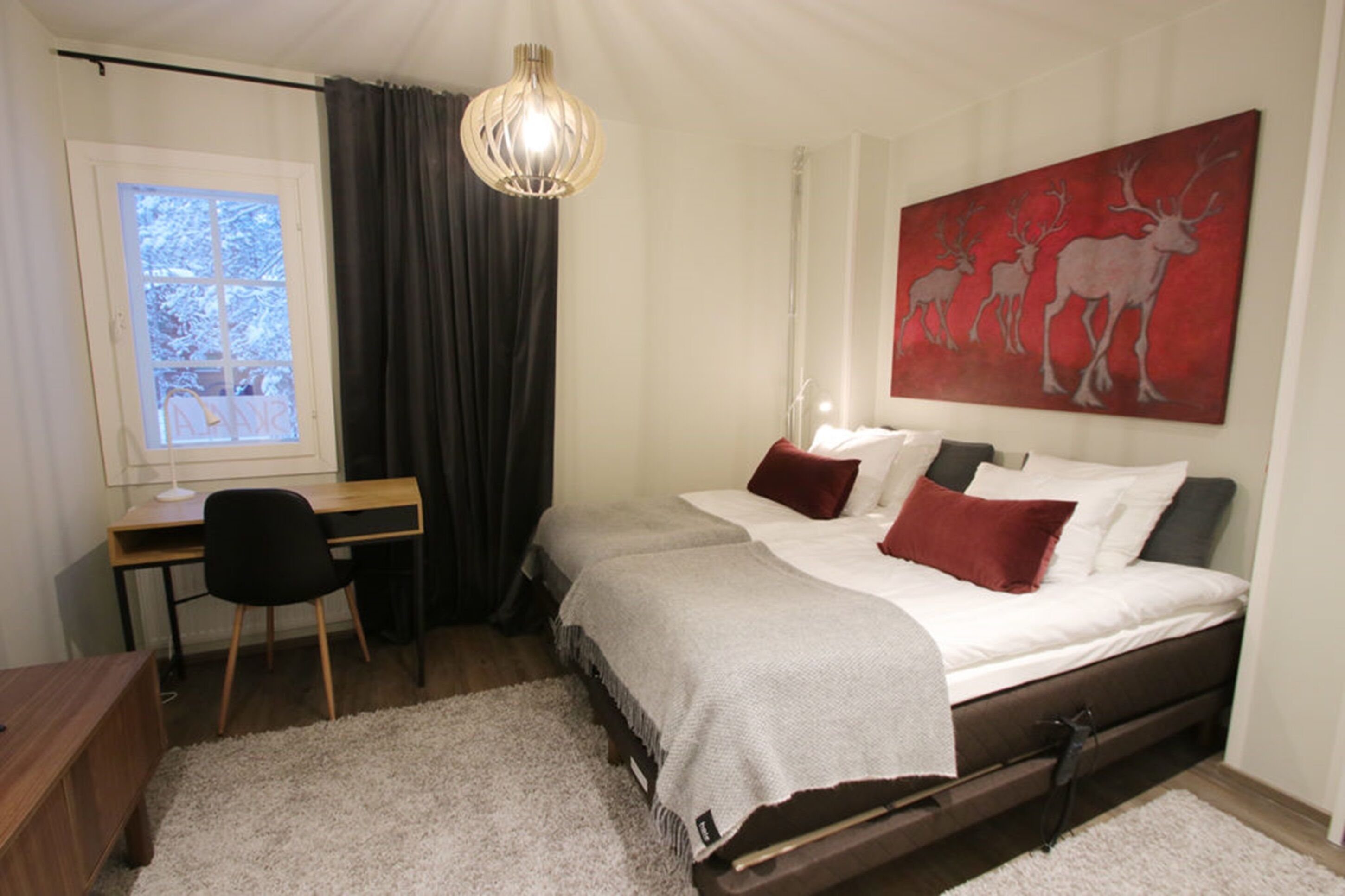 Een slaapkamer met een bed, een bureau, een stoel en een groot schilderij aan de muur.