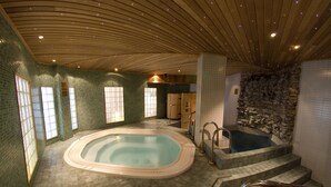 A large indoor swimming pool with a stone wall and a wooden ceiling. - Hotel Hullu Poro (Kittila)