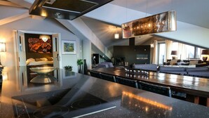 A modern kitchen with a central island, built-in appliances, and a dining area with a long table. - Hotel Hullu Poro (Kittila)