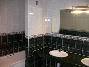 A bathroom with black and white tiles, two sinks, a mirror, and a toilet.