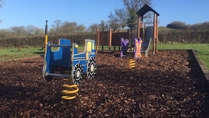 A playground with a blue tractor play structure and a small shelter. - Hunters Lodge Inn (Wincanton)