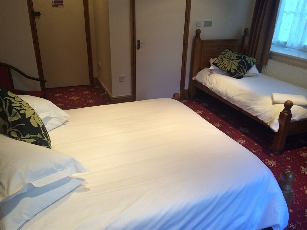 A bedroom with two beds, a wooden headboard, and a red carpet.