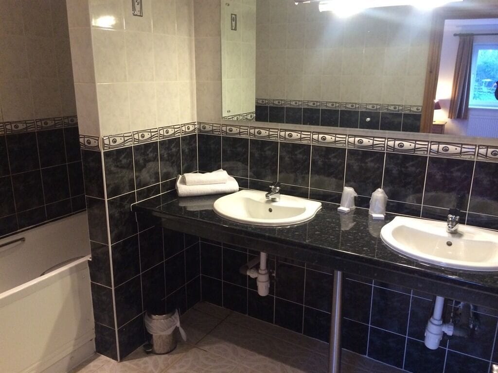 A bathroom with two sinks, a mirror, and a towel rack.