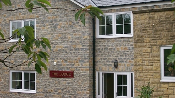 A stone building with a sign reading "THE LODGE". - Hunters Lodge Inn (Wincanton)