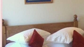 A bed with white bedding and two red pillows.