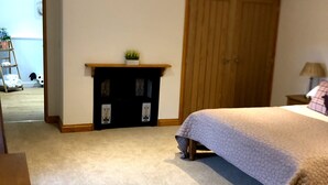 Una camera da letto con un letto grande, un armadio in legno, un camino e un pavimento tappezzato.
