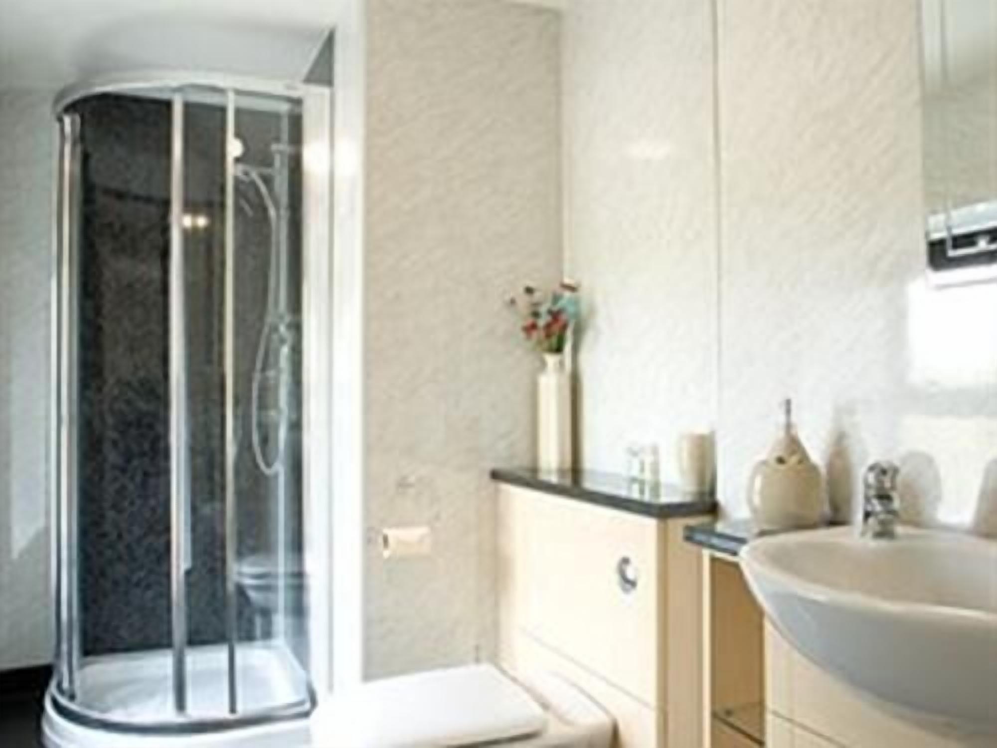 A modern bathroom with a glass shower enclosure, a white sink, and a marble-topped vanity.