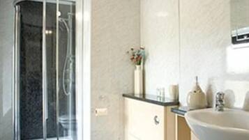 A modern bathroom with a glass shower enclosure, a white sink, and a marble-topped vanity.