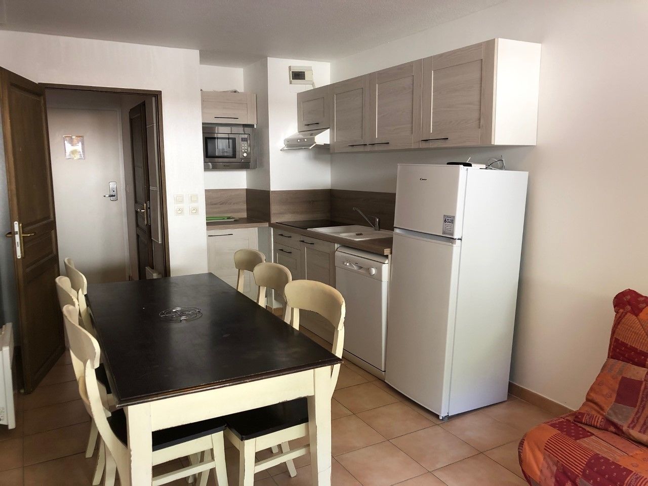 Eine kleine Küche mit Esstisch und Stühlen, inklusive Kühlschrank, Mikrowelle und Geschirrspüler.