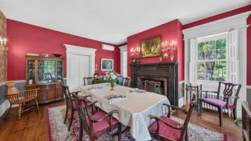 A dining room with a large table, chairs, a fireplace, and a window with a view.