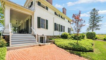 A two-story house with a covered porch and a brick pathway leading to the entrance.