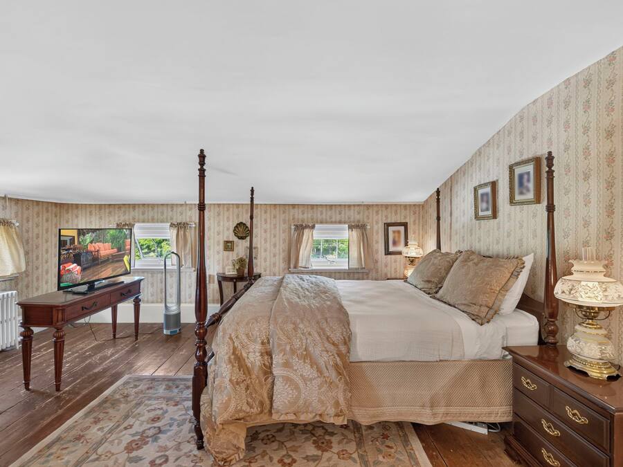 A bedroom with a four-poster bed, a desk, and a dresser.